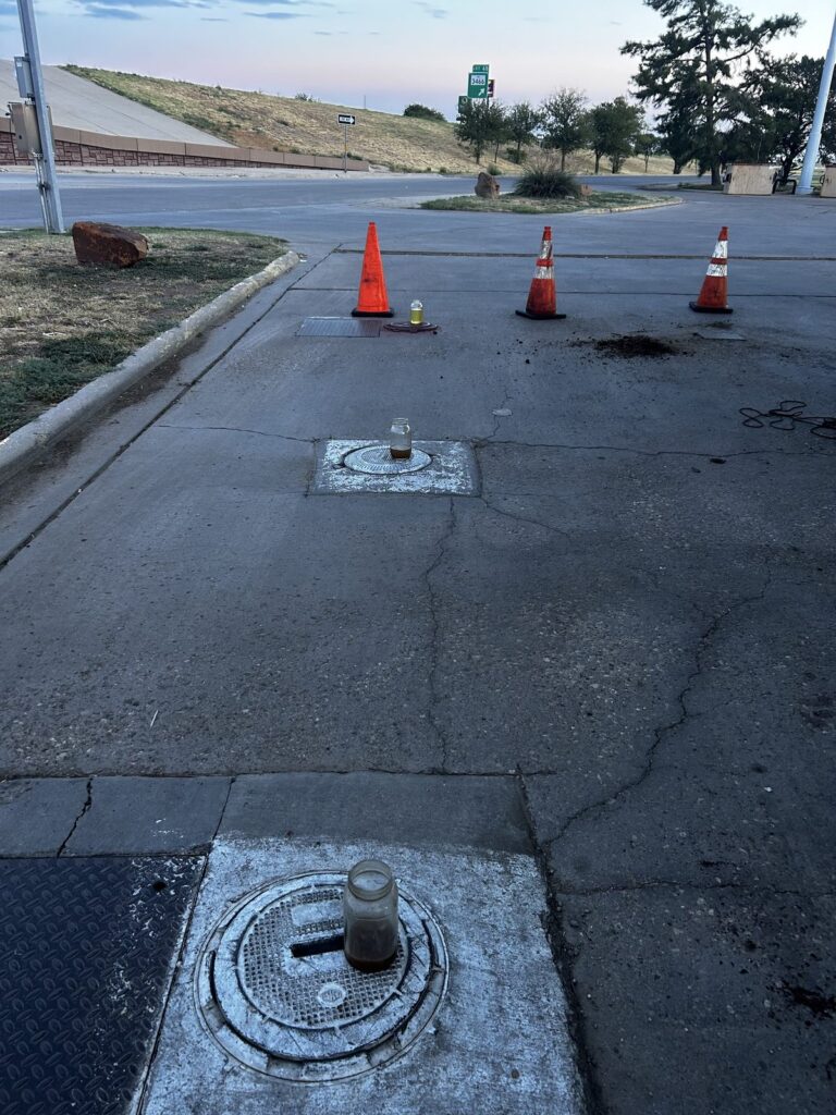 Mason jars of fuel set on tank fills beside traffic cones