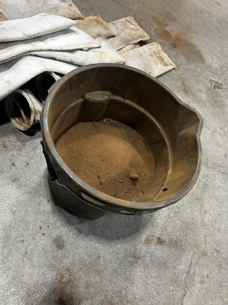 A bucket of fine sediment beside used filter socks